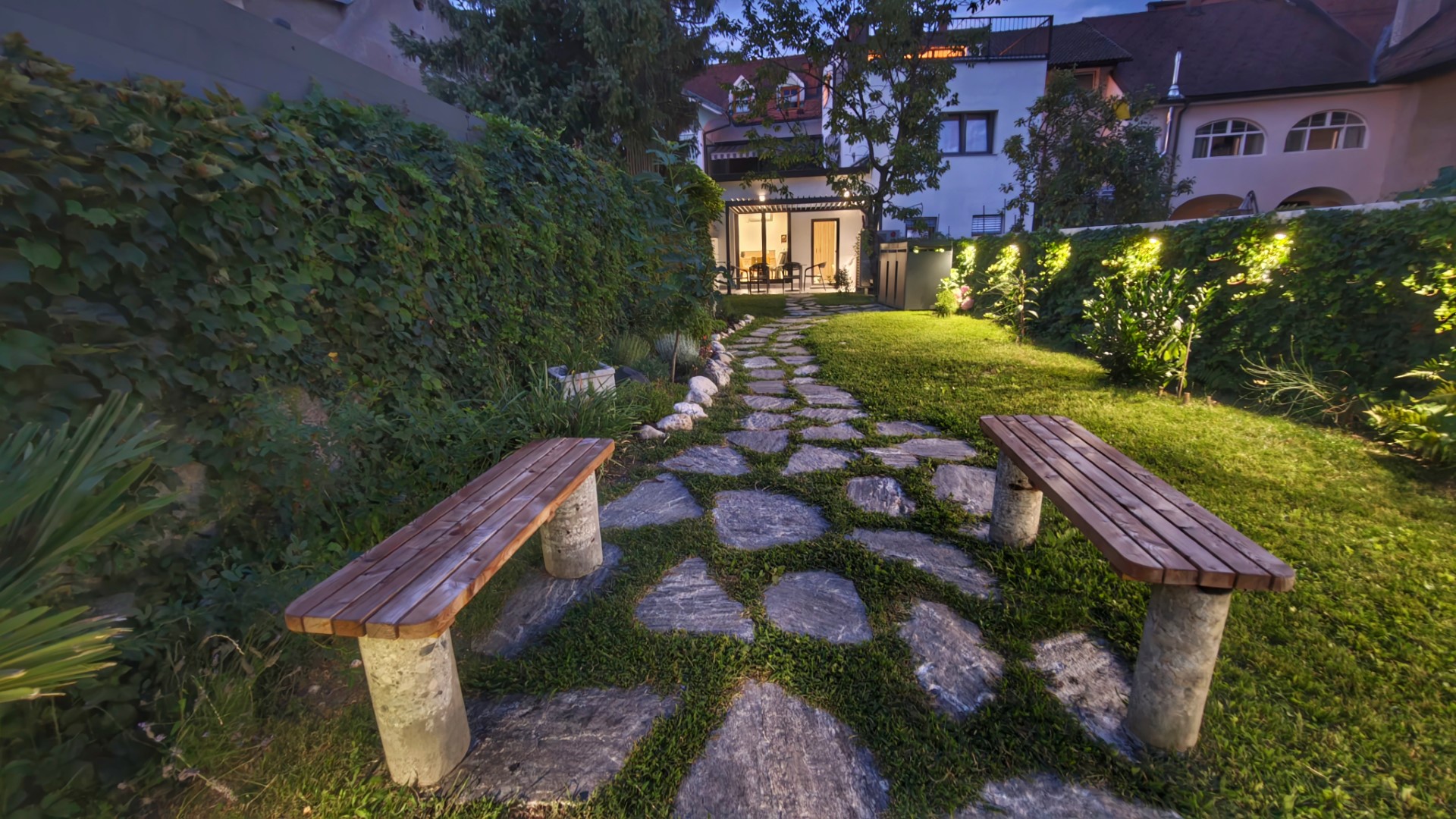 The garden of Hucho House at dusk, stone path and benches